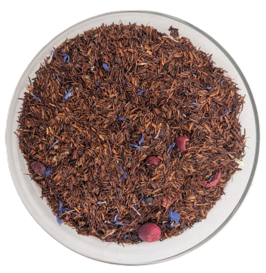 Eine Glasschale gefüllt mit loser Rooibos-Tee-Mischung, blauen Kornblumenblüten und getrockneten Heidelbeeren, aufgenommen auf weißem Hintergrund.