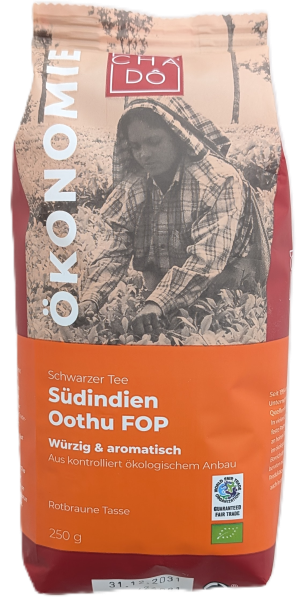 Cha Dô Ökonomie Bio Schwarztee Südindien Oothu FOP Verpackung in Orange-Rot mit Bild einer Teepflückerin. Bildbeschreibung: Tee-Verpackung von Cha Dô mit orange-rotem Sockel, Schwarz-Weiß-Aufnahme einer indischen Teepflückerin sowie Bio- und Fairtrade-Sie