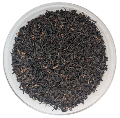 Draufsicht auf feine, gerollte und dunkle Bio-Assam-Satrupa-Schwarzteeblätter in einer Schale.