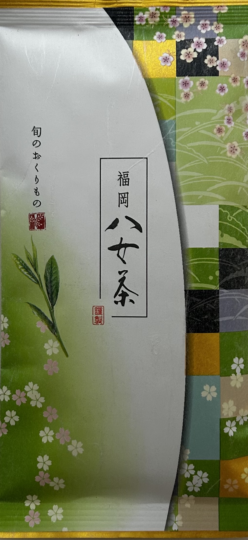 Die Originalverpackung des japanischen Grüntees "Sencha Midori No. 2". Es handelt sich um eine schlanke, hochformatige Teetüte mit einem eleganten, traditionell japanischen Design. Die Verpackung ist asymmetrisch gestaltet und wird oben von einem edlen, g