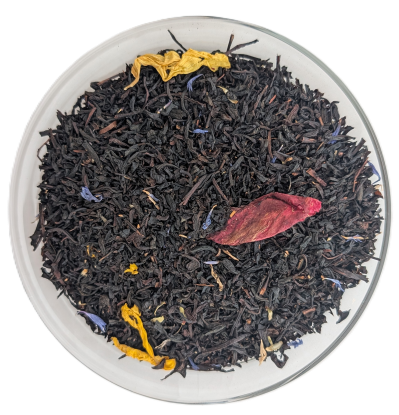 Dunkle lose Schwarzteeblätter mit farbigen Akzenten aus blauen Kornblumenblüten, gelben Blütenblättern und einem großen roten Rosenblütenblatt.