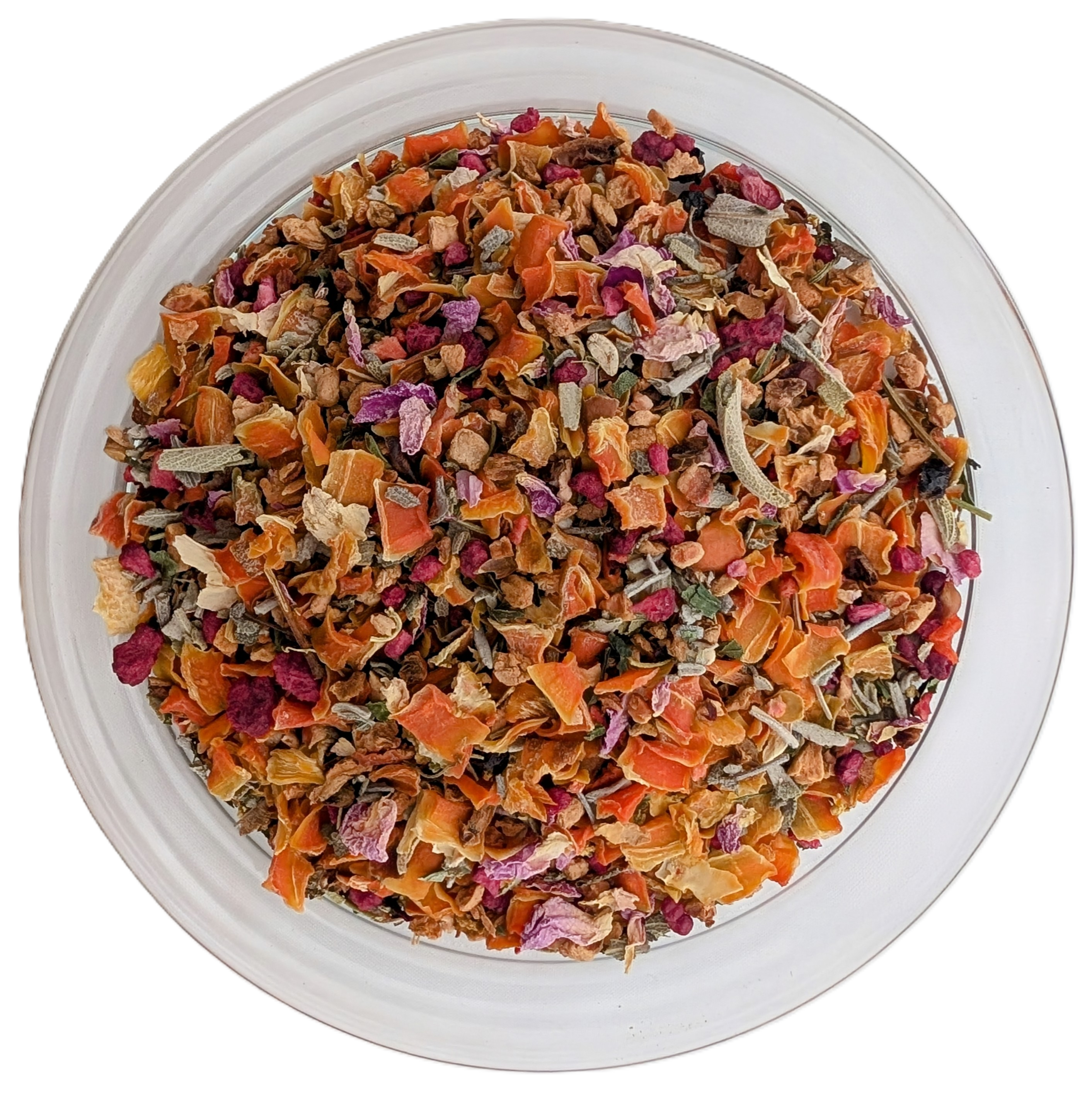 Eine runde, durchsichtige Glasschale aus der Vogelperspektive, gefüllt mit einer grob geschnittenen Teemischung. Die Optik ist stark geprägt von vielen hellorangefarbenen Karottenflocken und Apfelstücken, gemischt mit dunkelroten Hibiskusteilen, violetten