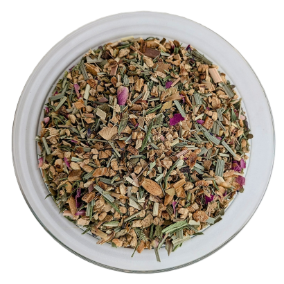 Eine runde Glasschale aus der Vogelperspektive, gefüllt mit einer grob geschnittenen Kräuterteemischung. Das optische Bild wird von unzähligen kleinen, faserigen, hellbraunen Ingwerstücken und quer geschnittenen, grün-beigen Halmen von Zitronengras bestim