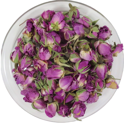 Eine runde Glasschale, gefüllt mit ganzen, getrockneten Bio-Rosenknospen. Die geschlossenen Knospen mit magentafarbenen Spitzen und grünen Kelchblättern sind von oben fotografiert.