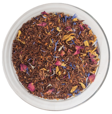 Lose Rooibos-Tee-Mischung mit getrockneten rosa Rosenblüten, blauen Kornblumen und gelben Ringelblumenblättern, serviert in einer klaren Glasschale auf weißem Hintergrund.