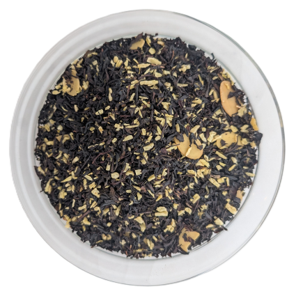 Loose-Leaf-Schwarztee vermischt mit gehackten Mandeln, hellen Holz- oder Gewürzstückchen und gehobelten Mandelblättchen in einer runden Schale von oben fotografiert.