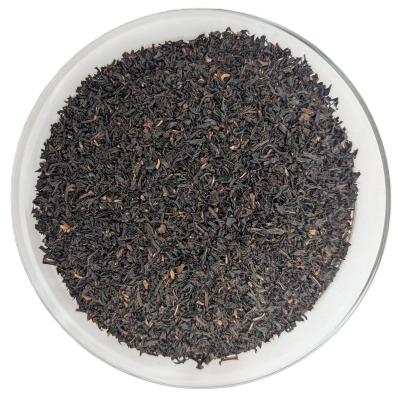 Assam Bari Schwarztee – gleichmäßiges, dunkelbraunes bis schwarzes Broken-Teeblatt in einer transparenten Schale aus der Draufsicht.