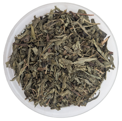 Flache, grün-braune entkoffeinierte Bio-Sencha-Teeblätter in einer transparenten Schale.